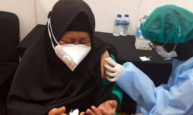 Arsip foto. Seorang lansia berdoa saat sedang menjalani suntikan dosis pertama vaksin COVID-19.